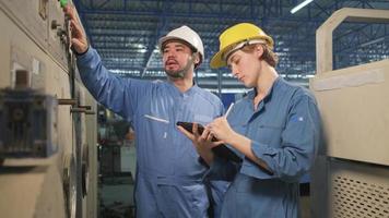 professionelle ingenieurteams der industrie in schutzhelmen und sicherheitsuniformen inspizieren das bedienfeld der maschine, wartungsprüfung mit tablet in der mechanischen fabrik, elektrische servicebesetzung. video