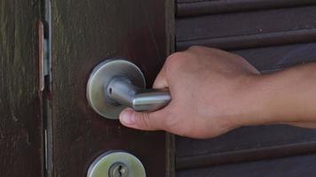 close-up da mão de uma mulher abrindo uma porta. porta de madeira com puxador de metal cromado video