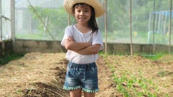una niña con sombrero ayuda a su madre en el jardín, una pequeña jardinera. linda chica jugando en el huerto. video