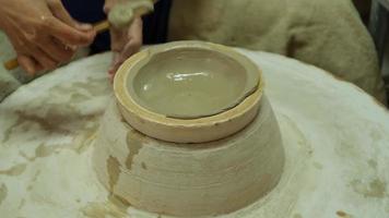 primo piano di una donna che lavora su un tornio da vasaio che fa oggetti di argilla nel laboratorio di ceramiche. il processo di formazione di una ciotola di ceramica fatta a mano. video