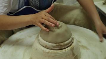 close-up de uma mulher trabalhando na roda de oleiro fazendo objetos de barro na oficina de cerâmica. o processo de formação de uma tigela de cerâmica artesanal. video