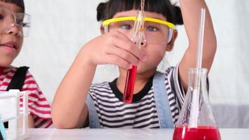 los niños están aprendiendo y haciendo experimentos científicos en el salón de clases. dos hermanitas jugando al experimento científico para la educación en el hogar. Experimentos científicos fáciles y divertidos para niños en casa. video