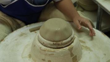 primo piano di una donna che lavora su un tornio da vasaio che fa oggetti di argilla nel laboratorio di ceramiche. il processo di formazione di una ciotola di ceramica fatta a mano. video