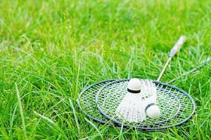 Shuttlecock and badminton rackets on a green lawn photo