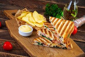 Club sandwich with ham, cheese, tomato, salad and chips photo