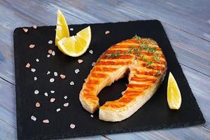 Grilled salmon fish on stone board. Salt atlantic salmon fried on grill with lemon photo