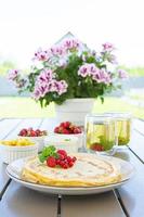 Pancakes with caramelized apples, raspberries, strawberries and red currants. Brunch with green tea and crepes. photo