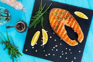 Grilled salmon fish on stone board. Salt atlantic salmon fried on grill with lemon. Top view photo