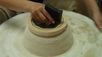 primo piano di una donna che lavora su un tornio da vasaio che fa oggetti di argilla nel laboratorio di ceramiche. il processo di formazione di una ciotola di ceramica fatta a mano. video