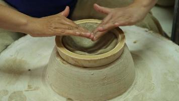 primer plano de una mujer que trabaja en un torno de alfarero haciendo objetos de arcilla en un taller de cerámica. el proceso de formación de un cuenco de cerámica hecho a mano. video