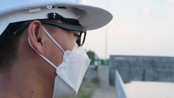 junger asiatischer ingenieur, der einen helm und eine maske trägt, sieht aus und lächelt video