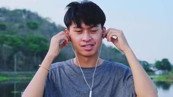 Happy young Asian man wearing earphone. video