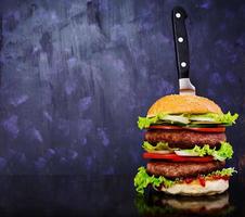 Delicious handmade burger on dark background. Close view photo