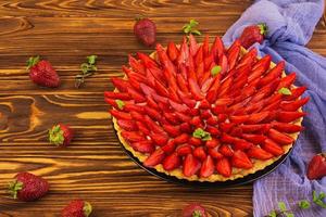 Delicious tart with strawberry on wooden background photo