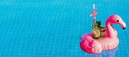 Fresh coctail mojito on inflatable pink flamingo toy at swimming pool. Vacation concept. photo