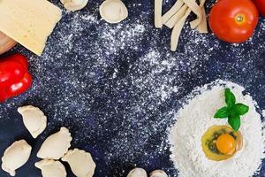 Raw pizza dough with ingredients and spices on dark background. Top view photo