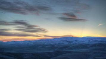 8k Sonnenaufgang hinter dem schneebedeckten Hügel an einem kalten Wintermorgen video
