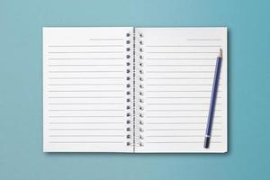 Notebooks and pencils are placed on a blue paper surface. photo