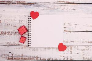 Paper heart with red box and book on wooden floor photo