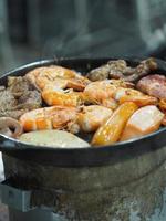 sartén de acero asado con camarones en estufa de carbón foto