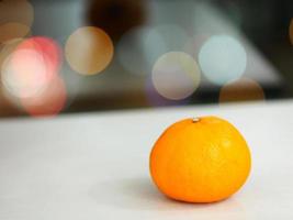 fruta naranja sobre mesa blanca sobre fondo bokeh foto