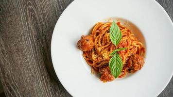 Top view of View Spaghetti meatballs with tomato sauce in white plate on wooden table photo