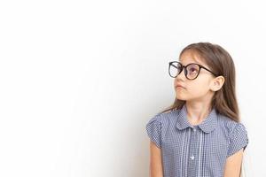 una niña de 7 años con gafas con caras tristes. educación infantil, concepto de aprendizaje con espacio de copia foto