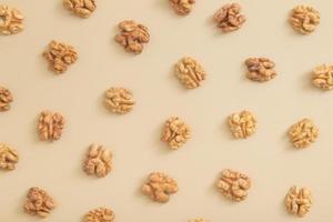 Pattern with peeled halves of walnuts top view. Food abstract background with nuts photo