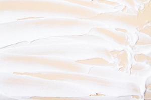 White cream brush strokes top view on beige background photo