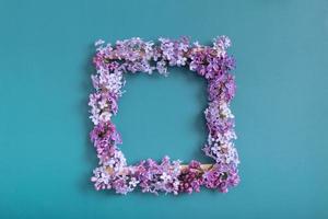 Summer or spring composition on a turquoise background. Lilac flowers square with copy space top view. Summer, spring floral concept photo