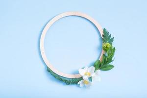 Summer or spring composition on a blue background. Wooden frame and anemone flowers and leaves with copy space top view. Summer, spring floral concept photo