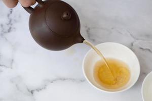 Tea from the teapot is poured into a cup. Tea ceremony concept photo