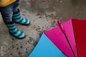 Legs in rubber boots and a colored umbrella. Rainy weather concept photo