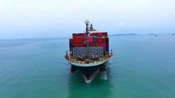 Aerial in front view of cargo ship carrying container and running with tug boat for export  goods  from  cargo yard port to custom ocean concept freight shipping by ship . video