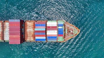 Aerial top view of smart cargo ship carrying container and running very fast for export cargo from container yard port to custom ,Contrail line in the ocean by large ship very fast.