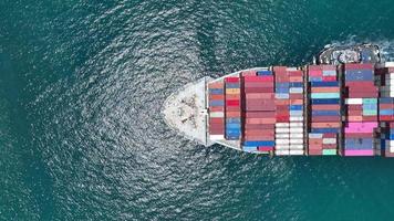 Aerial top view of smart cargo ship carrying container and running very fast for export cargo from container yard port to custom ,Contrail line in the ocean by large ship very fast.