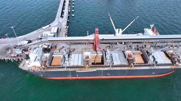 Luftaufnahme des Frachtcontainerschiffs unter dem Kran am internationalen Frachthafen unter dem Kranladetank für den Exportfrachtversand per Schiff.