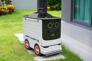 Autonomous parcel delivery robot parked in front of customer house, Smart transportation 5G technology concept photo