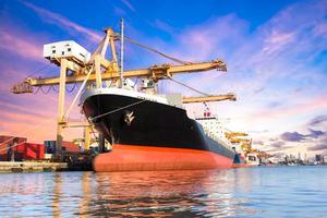 Container cargo freight ship with working crane loading bridge in shipyard at twilight for logistic Import export background photo