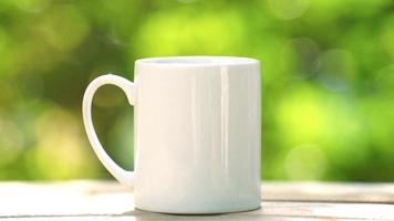 concepto de bebida de café caliente, café caliente humeante de primer plano, taza de café blanca de cerámica caliente con humo en una mesa de madera antigua en un fondo natural. video
