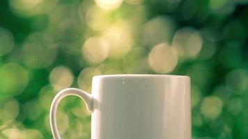 concetto di bevanda calda al caffè, caffè caldo fumante primo piano, tazza di caffè bianca in ceramica calda con fumo su un vecchio tavolo di legno in uno sfondo naturale. video