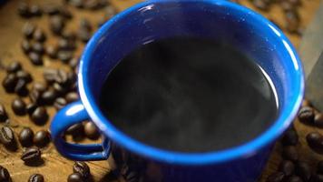 grano de café en el suelo de madera antiguo y una taza de café esmaltada con humo. juego de café con cafetera. enfoque suave.