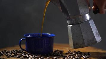 grano de café en el suelo de madera antiguo y una taza de café esmaltada con humo. juego de café con cafetera. enfoque suave. video