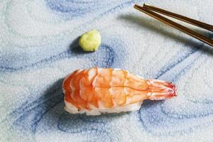 el sushi de gambas de comida japonesa en el plato tiene palillos. foto