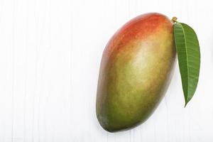 comida sana fruta de mango rojo tiene hoja sobre fondo blanco de mesa. foto