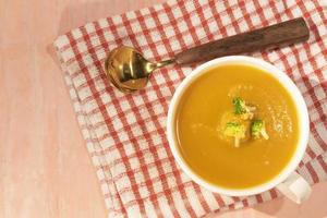 Healthy food Butternut squash and carrot soup in blow on orange table. photo