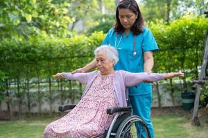 Doctor help Asian senior or elderly old lady woman patient exercise on wheelchair with happy in park. photo