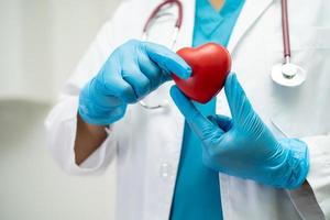 médico sosteniendo un corazón rojo en la sala del hospital, concepto médico fuerte y saludable. foto