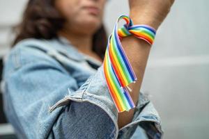 dama asiática con pulseras de la bandera del arco iris, símbolo del mes del orgullo lgbt celebran anualmente en junio las redes sociales de gays, lesbianas, bisexuales, transgénero, derechos humanos. foto