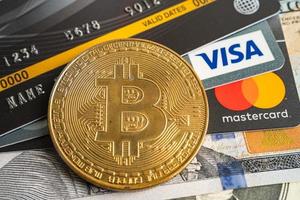 bangkok, tailandia, 9 de julio de 2021, bitcoin de oro con tarjeta de crédito en billetes de dólar estadounidense para intercambio electrónico mundial de dinero virtual, cadena de bloques, criptomoneda foto